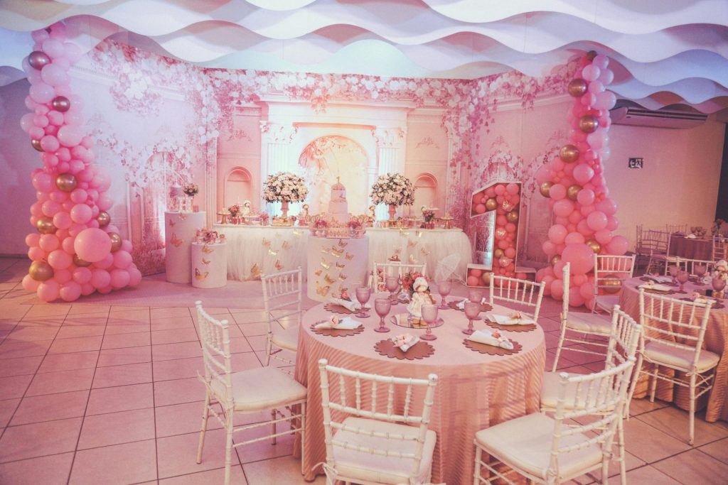 Una fiesta de cumpleaños bellamente decorada con temática rosa, arreglos florales y arcos de globos.