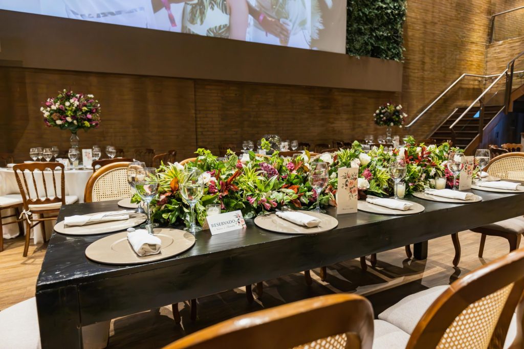 Mesa bellamente decorada en una recepción de boda de lujo en el interior con centro de mesa floral y vajilla sofisticada.